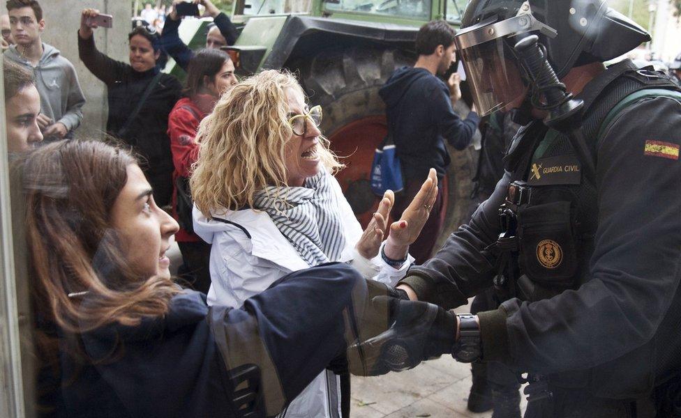 Two women argue with a Spanish National policeman during clashes between Catalan pro-independence people and police forces