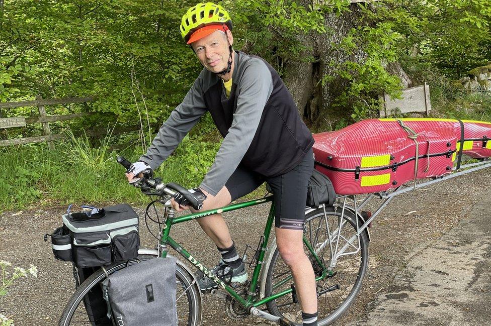 Kenneth on bike with cello behind