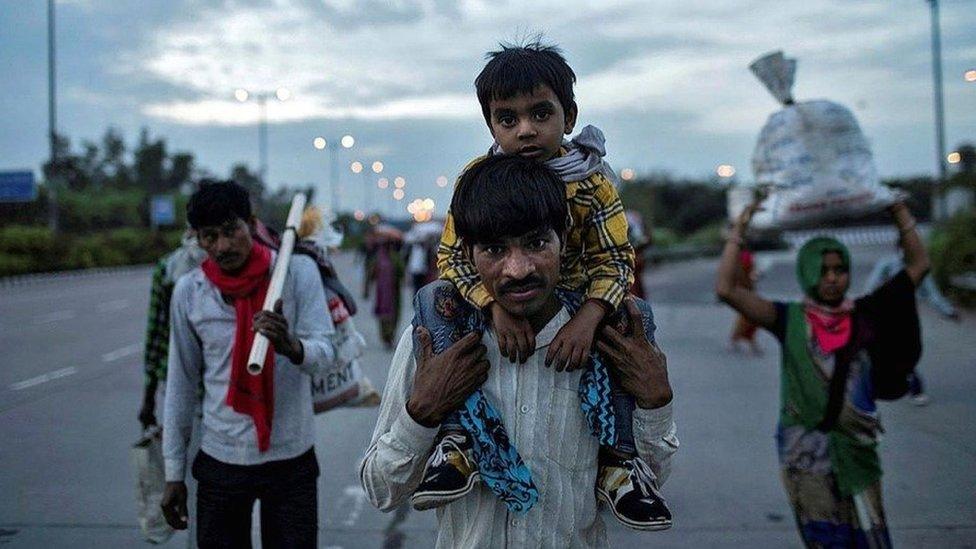 Dayaram Kushwaha carries his 5-year-old son, Shivam, as he and members of his extended family make their way back to his home village from New Delhi.