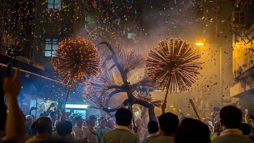 Members of the fire dragon dance team holding up the 'dragon' as it winds through the narrow streets in Hong Kong