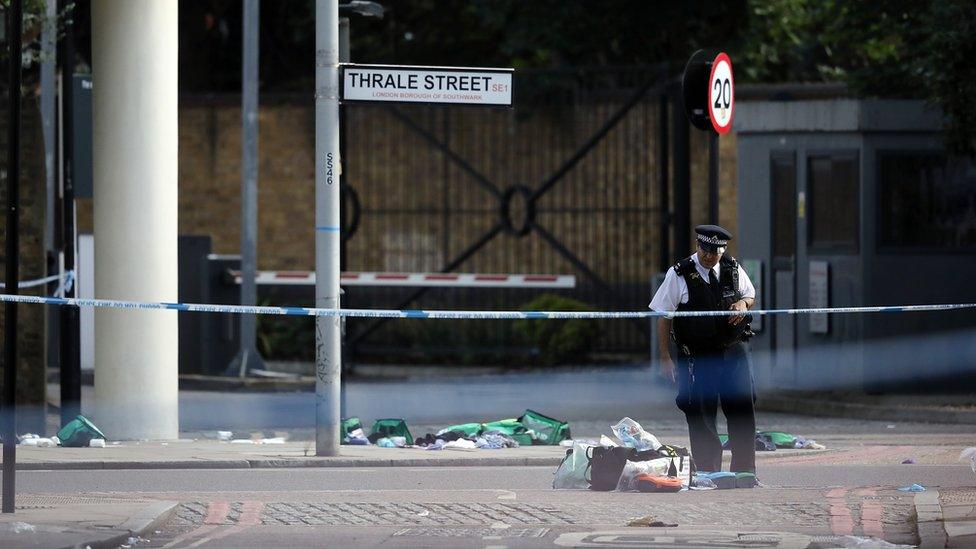 A police officer looks at debris on the road near Southwark Bridge