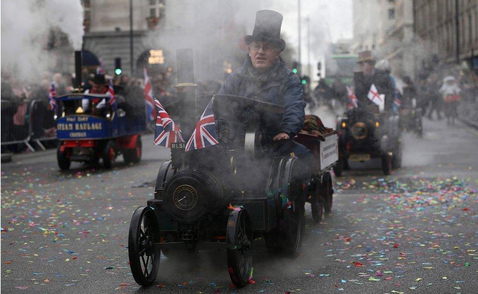 Men ride model steam engines