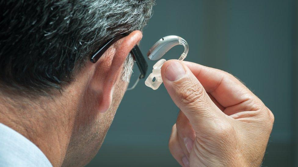 A man putting in his hearing aid