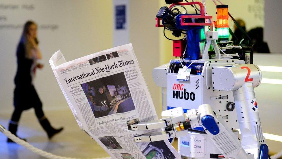 A robot holds a newspaper during a demonstration during the World Economic Forum (WEF) annual meeting in Davos, on January 22, 2016.