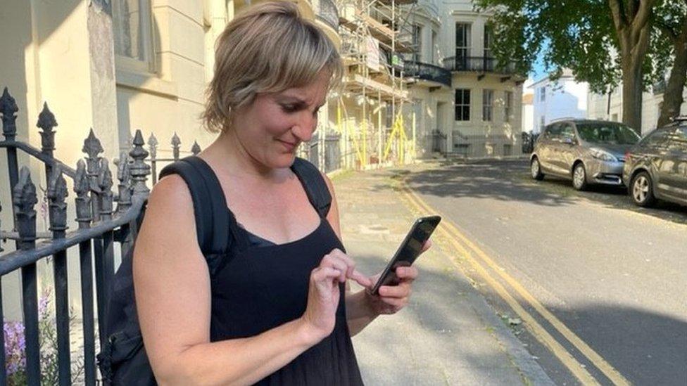 Emma Cohen on a street, trying to send a message on her phone