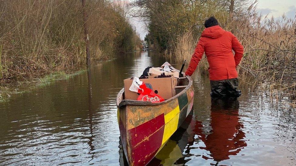 Man with canoe on a flooded road in Surlingham