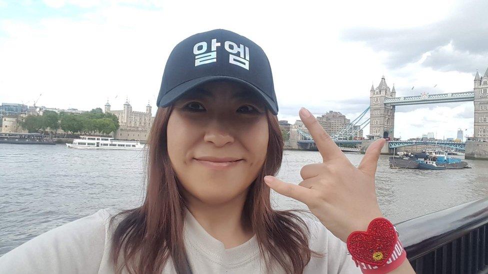 Rei in London, wearing RM hat in front of Tower Bridge