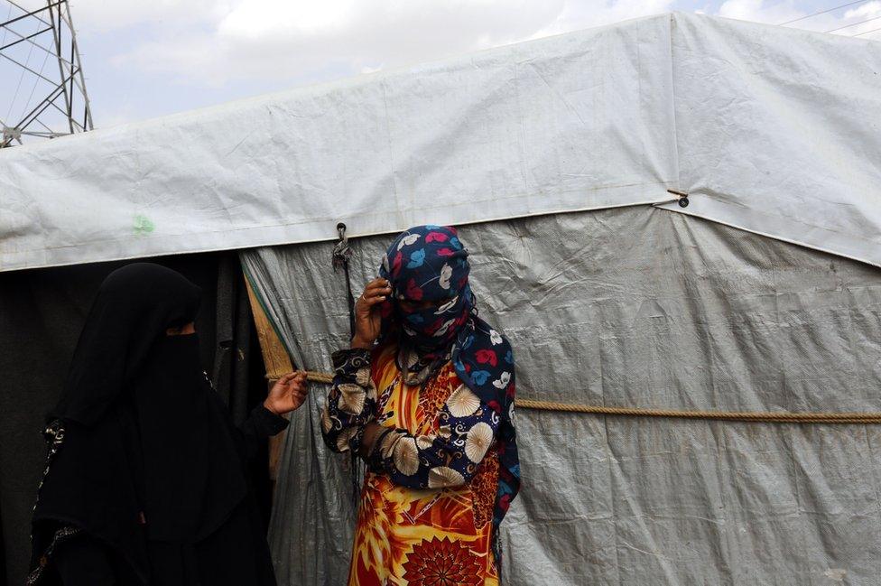 A woman covers her face with a headscarf