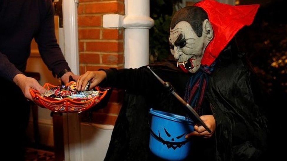 A child in fancy dress takes a sweet at Halloween