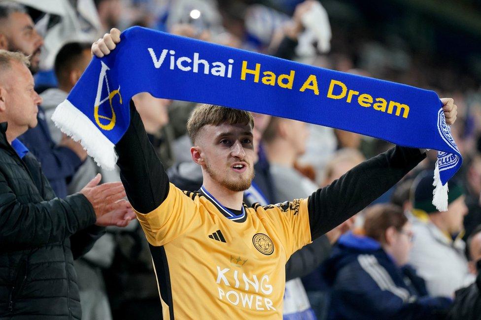 Leicester City fan holds up a scarf