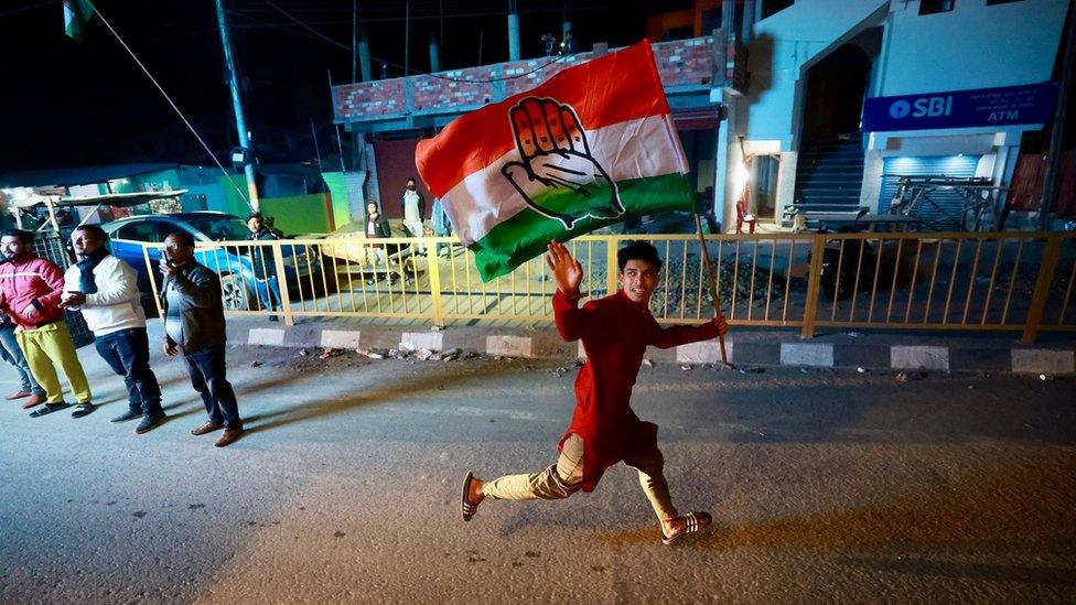 A young boy runs holding the Congress flag