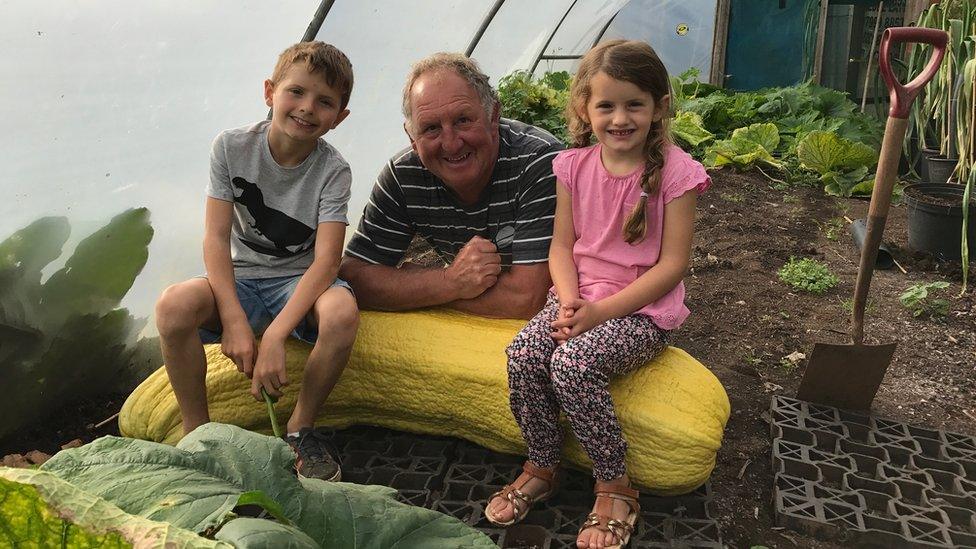 Phillip Vowles and his grandchildren Charlie and Sophia on top of a giant marrow