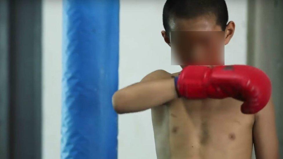 Child undoing boxing glove, still from the video documentary