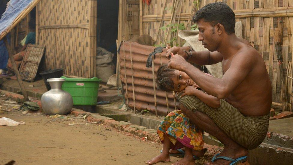 In this photograph taken on July 2, 2016, a Muslim Rohingya man cuts the hair of a child at one of the displacement camp in Sittwe located in western Myanmar's Rakhine State as they enter the final week of the holy month of Ramadan.