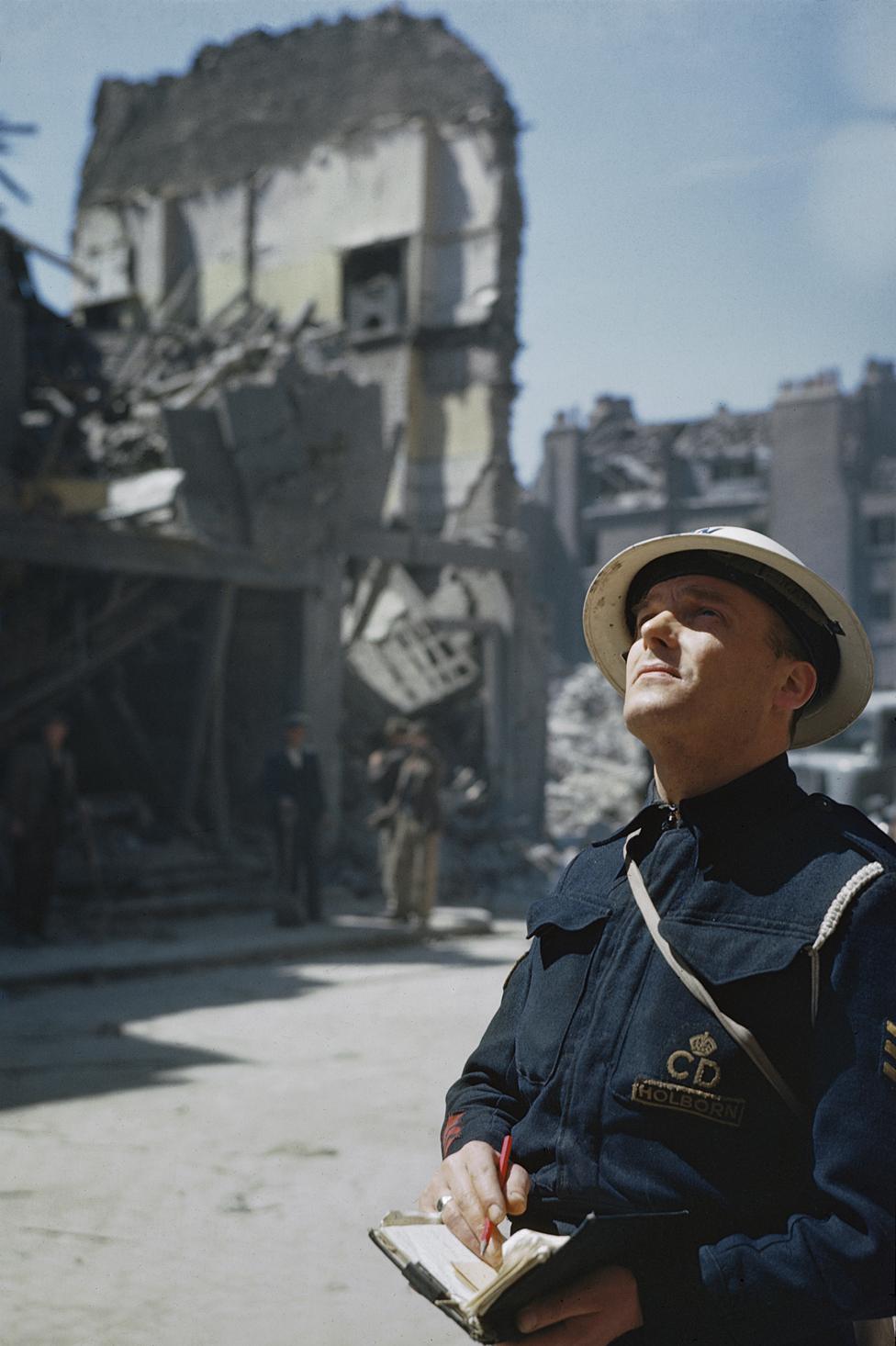 Civil Defence Warden inspects bomb damage in London