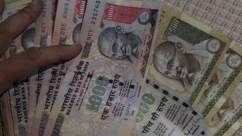 An Indian resident holds 500 and 1000 INR notes at her home in New Delhi on November 8, 2016.