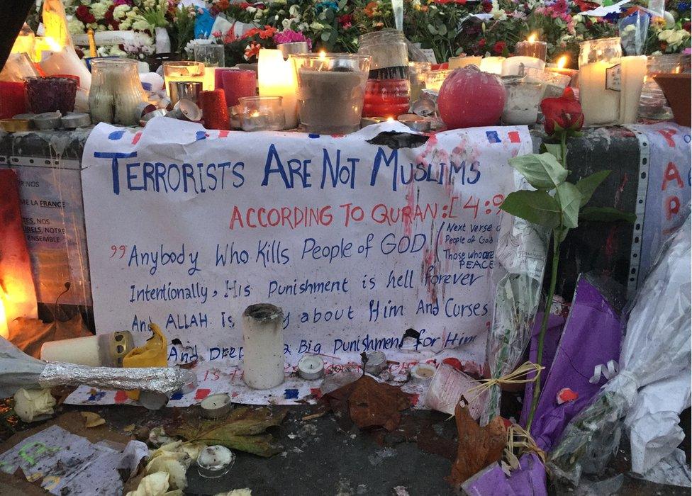 Memorial with candles and a sign reading: Terrorists are not Muslims