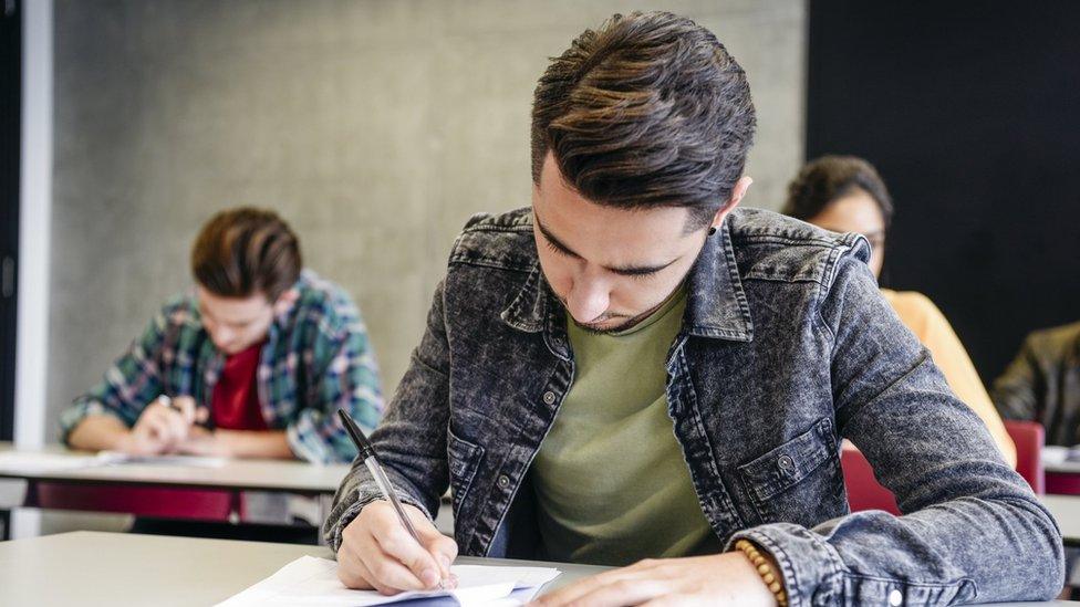 Male college student doing exam - stock photo