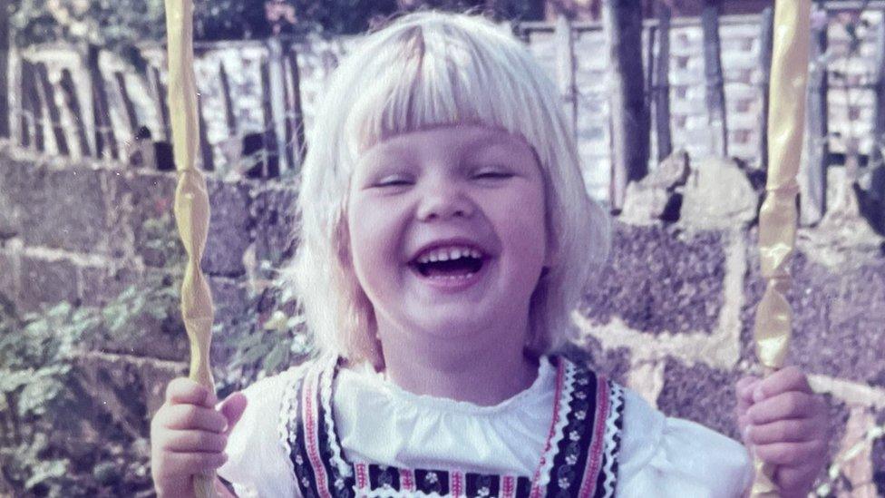 Kim Ovel as a child on a swing