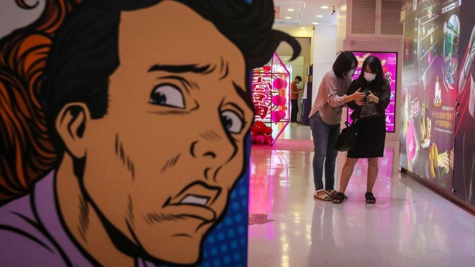 Two women wearing protective facemasks stand inside a shopping mall in Bangkok on 5 February 2020.