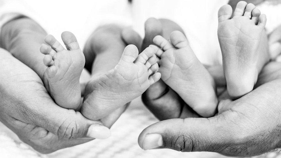 hands-holding-two-babies-showing-their-feet