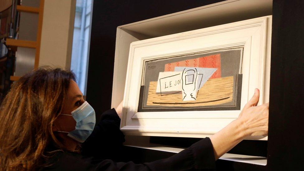 Raffle organizer Peri Cochin, wearing a protective face mask, poses with the Picasso's Nature Morte, during a charity raffle at Christie's auction house in Paris, 20 May 2020