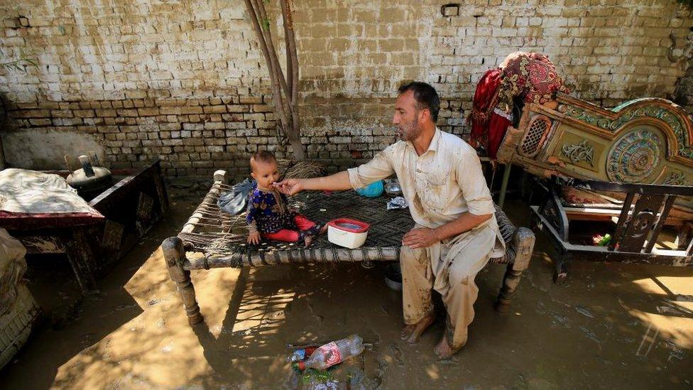 A man feeds his child in the aftermath of floods in Charsadda District, Khyber Pakhtunkhwa province, Pakistan, 28 August 2022.