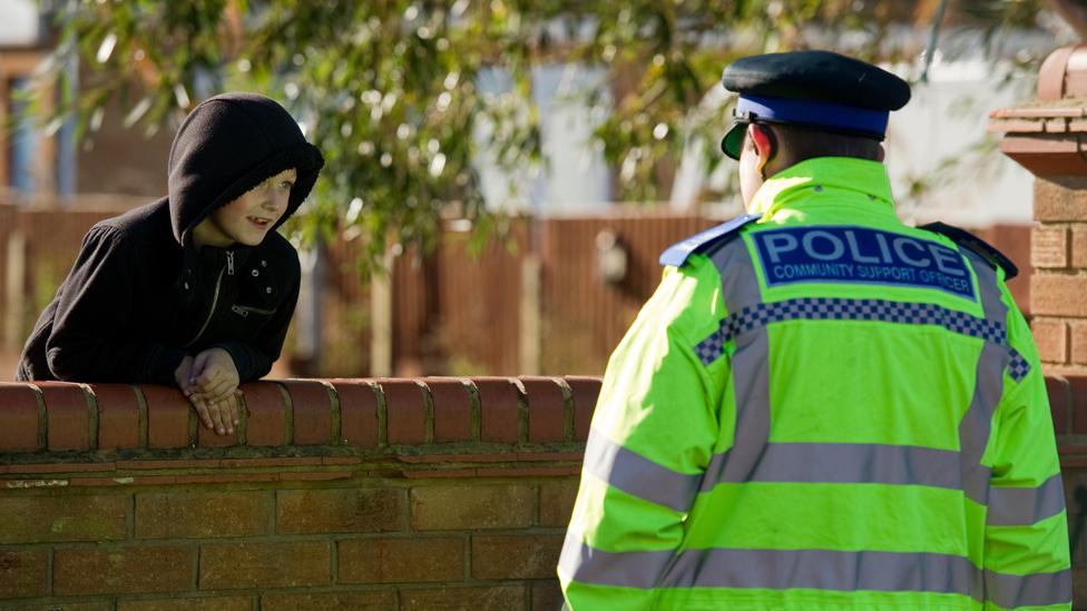 Police community support officer chats to young boy at a travellers' site