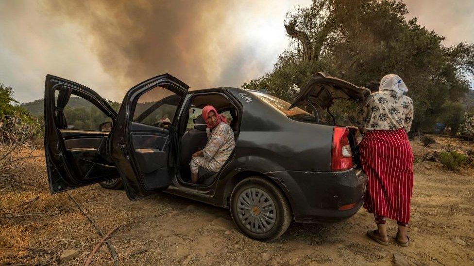 Women in or near car, with smoke behind them