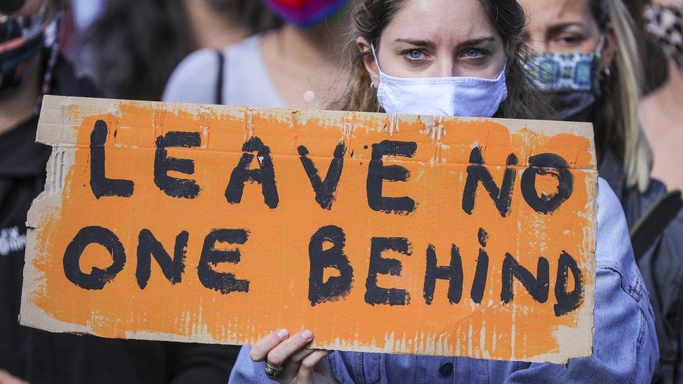 A demonstrator holds a banner reading 'LEAVE NO ONE BEHIND' as protesters gather to demand the immediate evacuation of Greek island refugee camps in Berlin