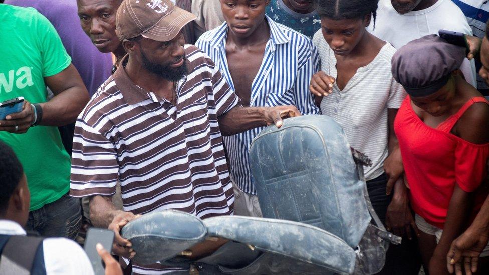 A man carries a seat near the site where a small plane crashed in Port-au-Prince, 20 April 2022