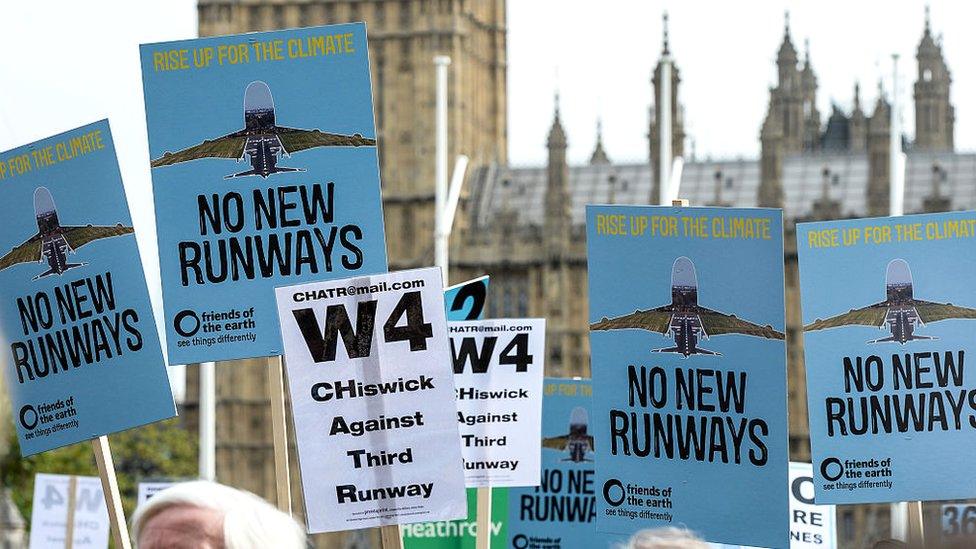 Protesters hold signs during a rally against a third runway at Heathrow airport, in Parliament Square in 2015