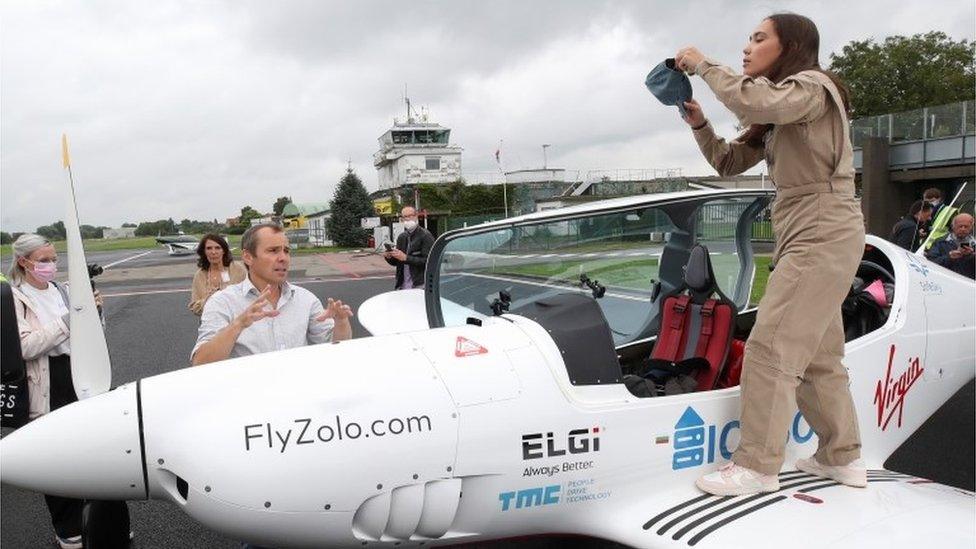 Zara Rutherford climbing into the cockpit of her aircraft while her father looks on