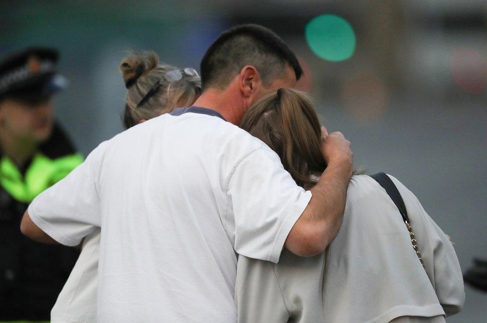 A man embraces a woman and a teenager as he collects them from the Park Inn Hotel where they were given refuge after last nights explosion at the Manchester Arena on 23 May 2017 in Manchester, England.