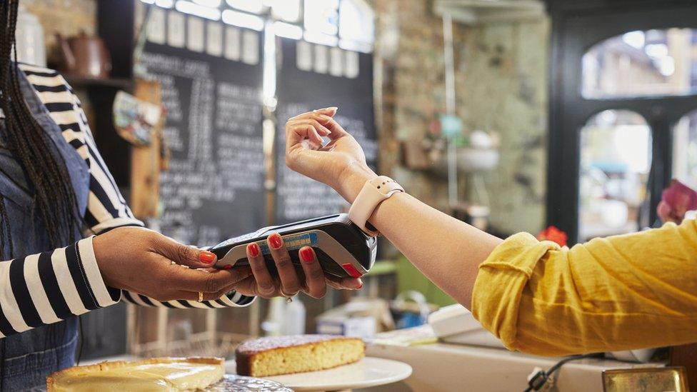 Person paying at cafe counter using smart watch