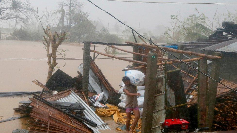 A resident carries a sack of rice from a damaged structure after Super Typhoon Haima destroyed his home in Vigan township, Ilocos Sur province in northern Philippines, 20 October 2016.