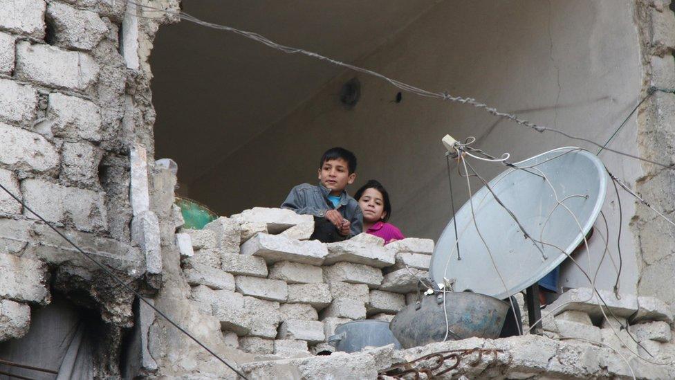 In this Thursday, Feb. 11, 2016 photo, children peer from a partially destroyed home in Aleppo, Syria.