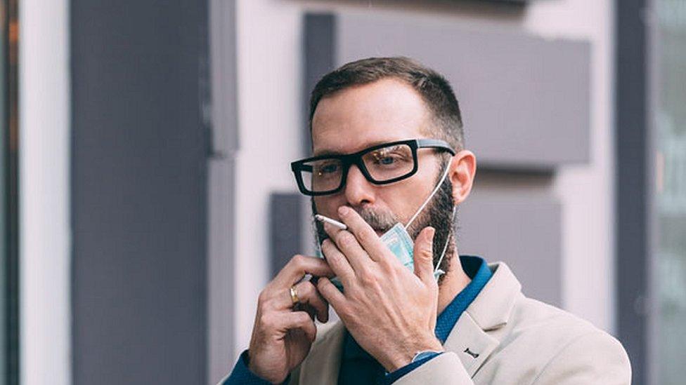 man smoking wearing mask