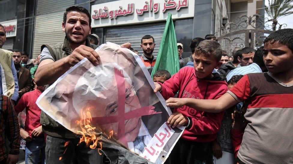 Hamas supporters burn a poster of Mahmoud Abbas at a protest against power cuts in Khan Younis, Gaza (14 April 2017)