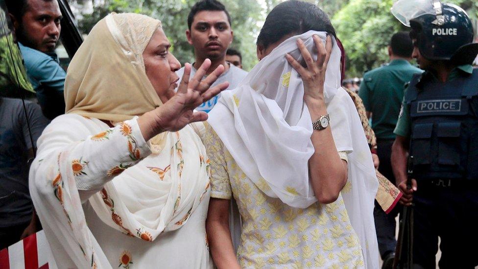 Relative try to console a woman whose son was missing after militants took hostages in a restaurant in Dhaka