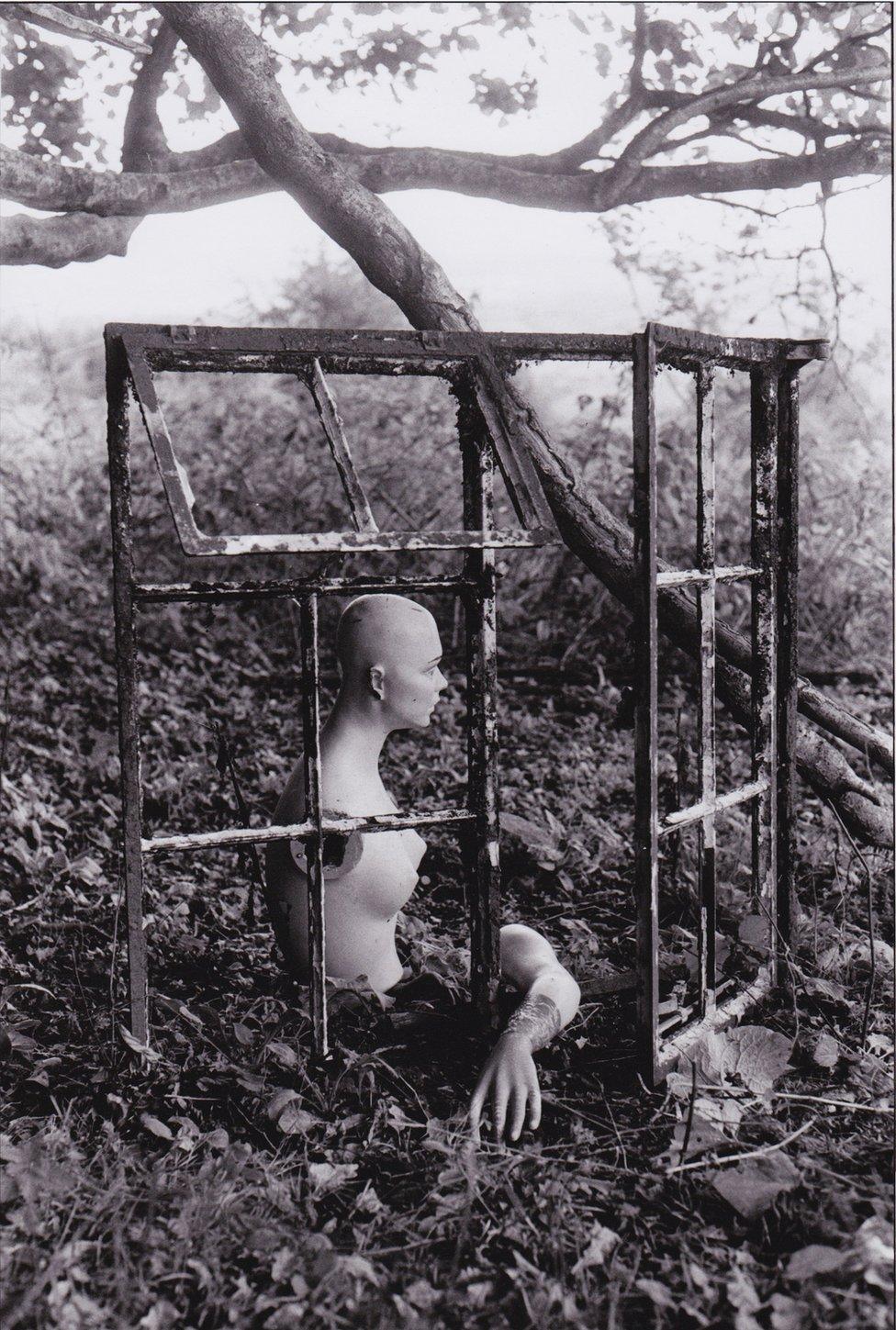 Old mannequin behind fly-tipped window frames