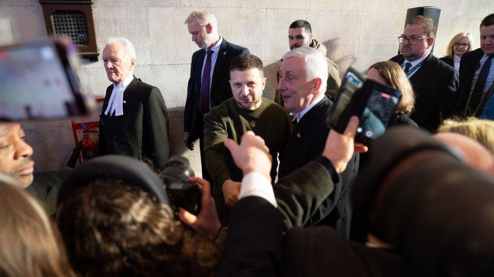 Ukrainian President Volodymyr Zelensky shakes hands with MPs as he walks with Speaker of the House of Commons, Sir Lindsay Hoyle, and Speaker of the House of Lords, Lord McFall, through the Palace of Westminster.