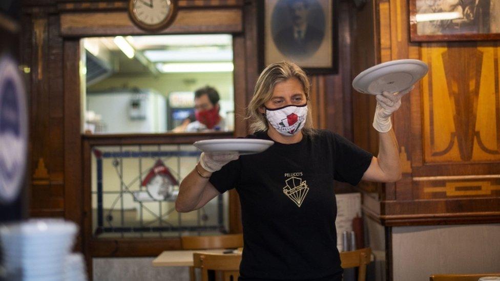 A woman in a cafe carrying plates