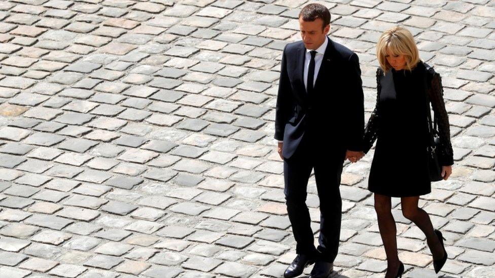 Mr Macron and his wife Brigitte holding hands