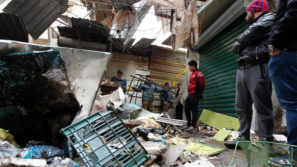 Iraqis look at the aftermath following a double blast in a busy market area in Baghdad's central al-Sinak neighbourhood on 31 December 2016.