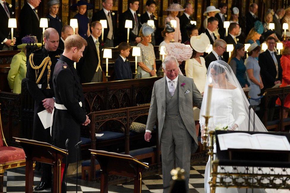 Prince Harry looks at his bride, Meghan Markle, as she arrives accompanied by the Prince of Wales