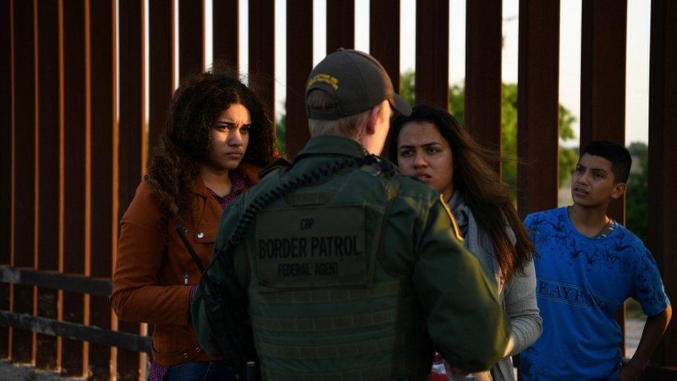 Migrants from Central America seeking asylum speak to a US official after crossing the Rio Grande river