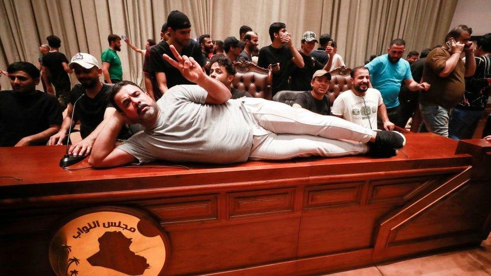 A supporter of the Iraqi cleric Moqtada al-Sadr lies on the desk of the speaker of the Iraqi parliament