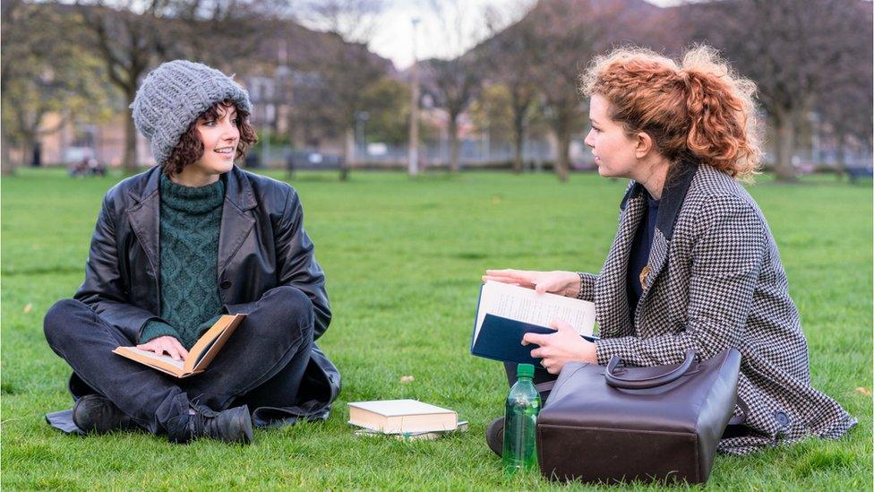 Two people sitting in a park talking