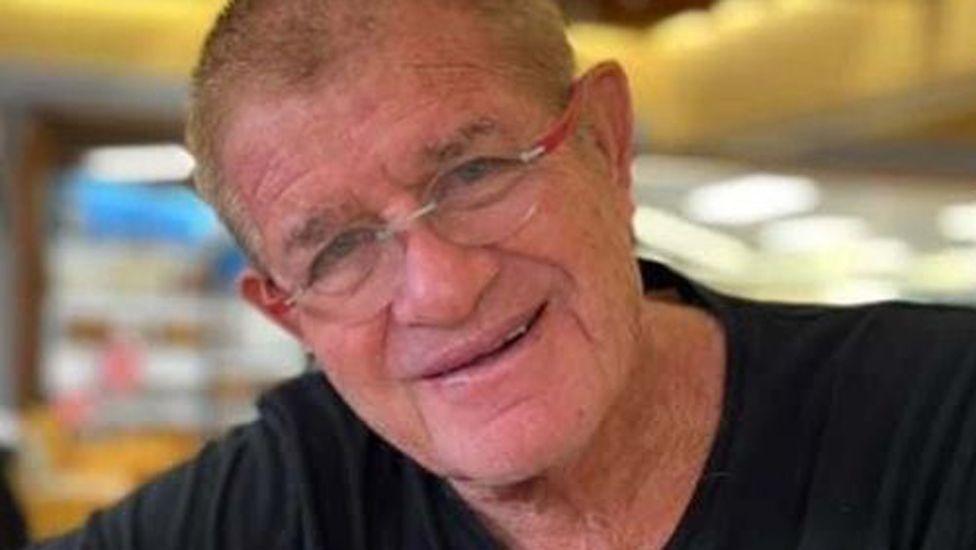 Meny Godard, who has short light-coloured hair, glasses with red frames and is wearing a black t-shirt